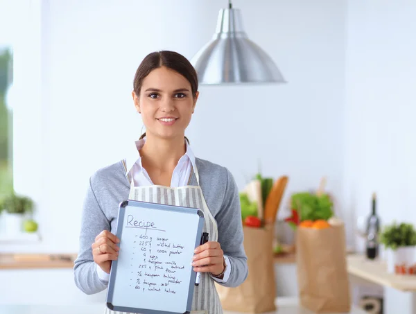 Femme dans la cuisine à la maison, debout près du bureau avec dossier — Photo