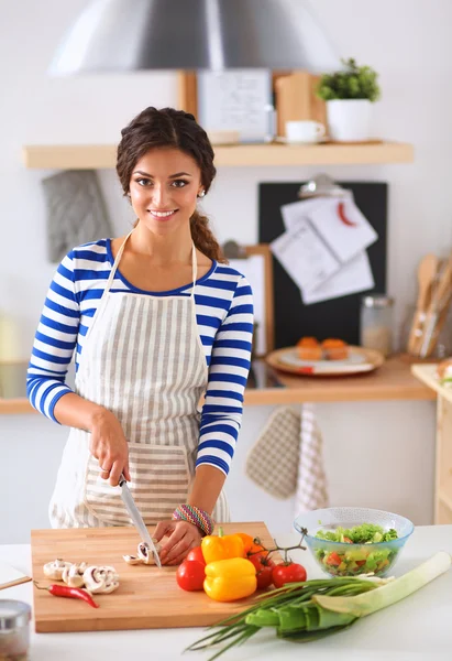 Mujer joven cortando verduras en la cocina — Foto de Stock