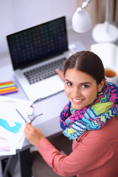 Junge attraktive Modedesignerin arbeitet am Schreibtisch und zeichnet, während sie mit dem Handy spricht — Stockfoto