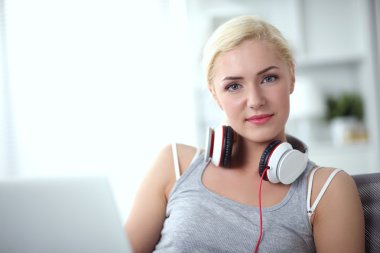 Evdeki genç ve güzel kadın kanepede oturup müzik dinliyor.