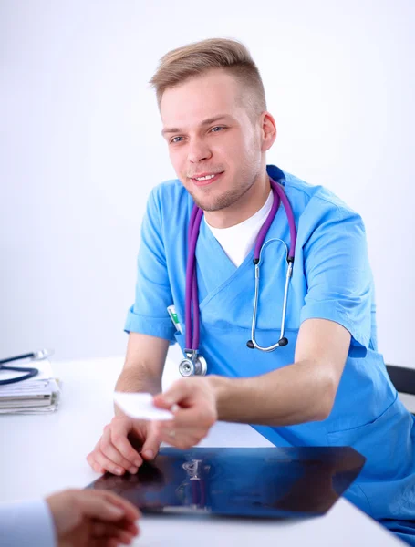 Retrato de um médico masculino sorridente com laptop sentado na mesa no consultório médico — Fotografia de Stock