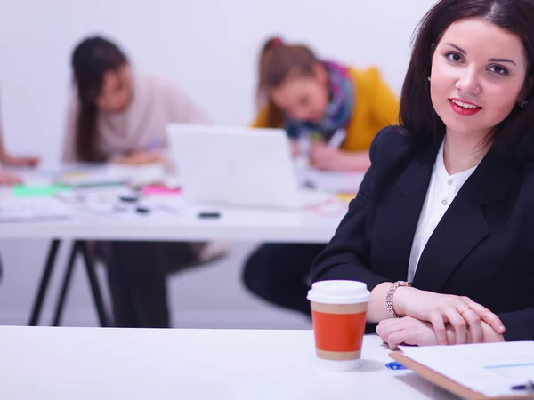 Attractive businesswoman sitting  on desk in the office with cup of coffee — Stock Photo, Image