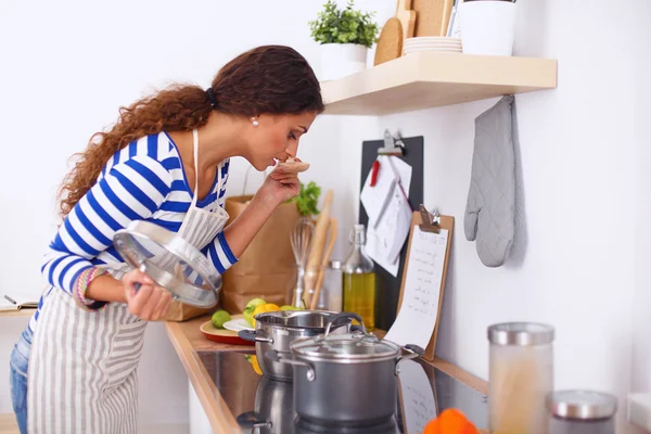 Mujer joven en la cocina preparando una comida — Foto de Stock