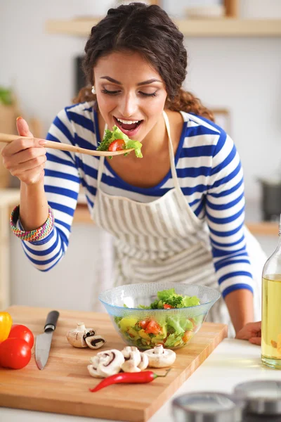 Genç kadın modern mutfakta taze salata yiyor. — Stok fotoğraf