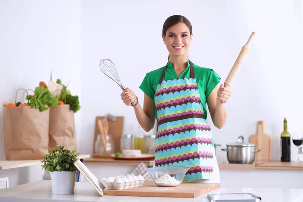 Smiling young woman standing in the kitchen — Stock Photo, Image