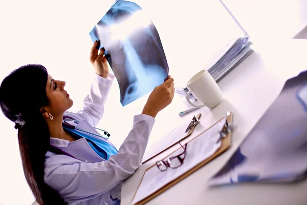 Jeune femme médecin étudiant l'image radiographique, assise au bureau — Photo