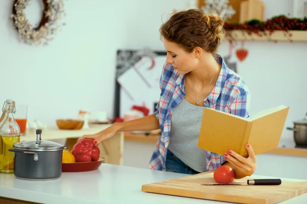 Mujer joven leyendo libro de cocina en la cocina, buscando receta —  Fotos de Stock