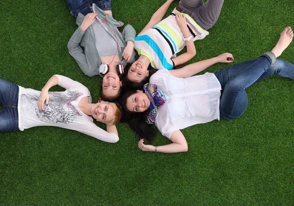 Čtyři mladé ženy leží na zelené trávě — Stock fotografie