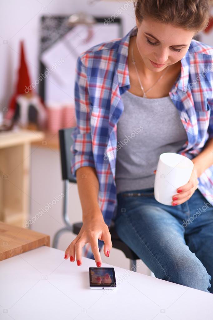 Smiling woman holding her cellphone in the kitchen