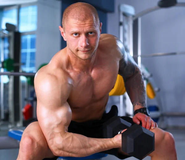 Strong man, bodybuilder exercising with dumbbells in a gym — Stock Photo, Image