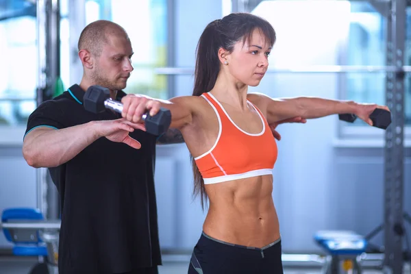 Hermosa mujer en el gimnasio haciendo ejercicio con su entrenador — Foto de Stock