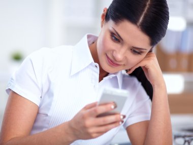 İş kadını ofiste oturan akıllı telefonuyla mesaj gönderiyor.