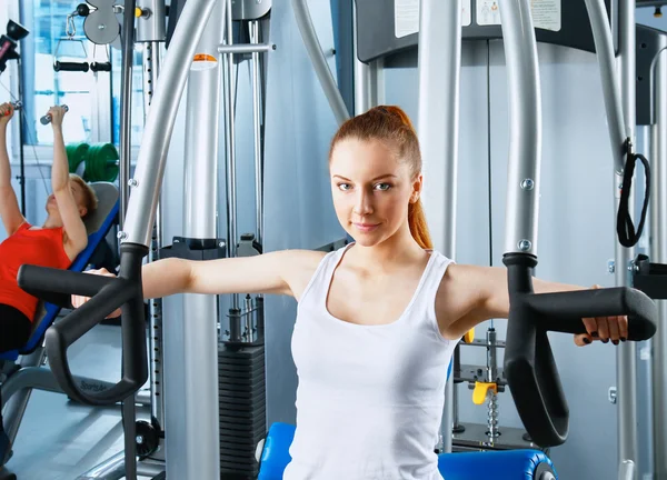 Belle fille à la salle de gym exercice sur les formateurs — Photo