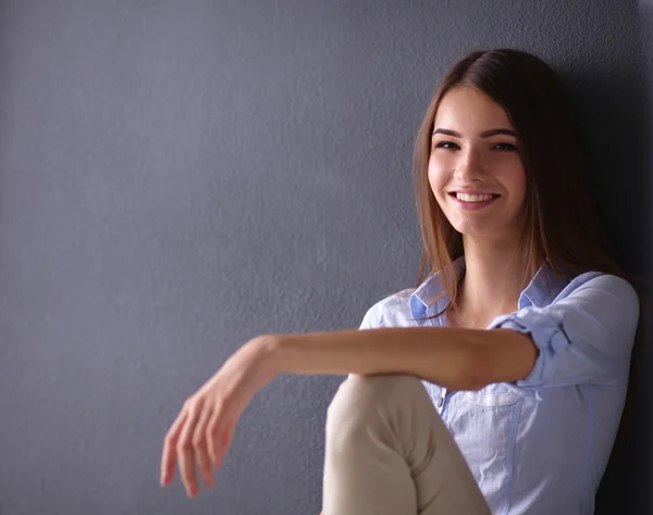 Jonge vrouw zit op de vloer in de buurt van donkere muur — Stockfoto