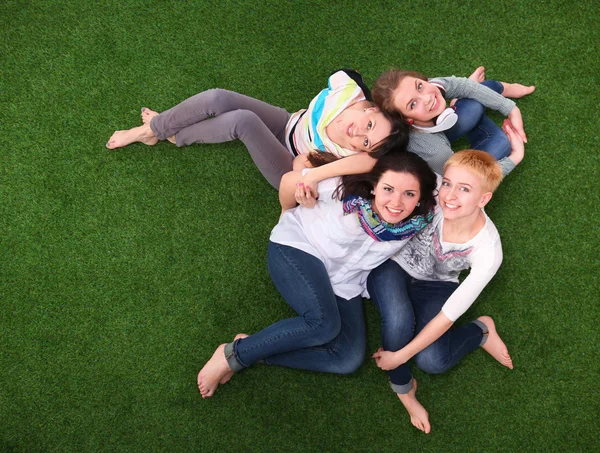 Quatro jovens mulheres sentadas na grama verde — Fotografia de Stock