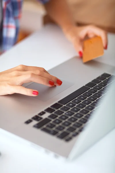 Mujer sonriente compras en línea utilizando la computadora y la tarjeta de crédito en la cocina —  Fotos de Stock