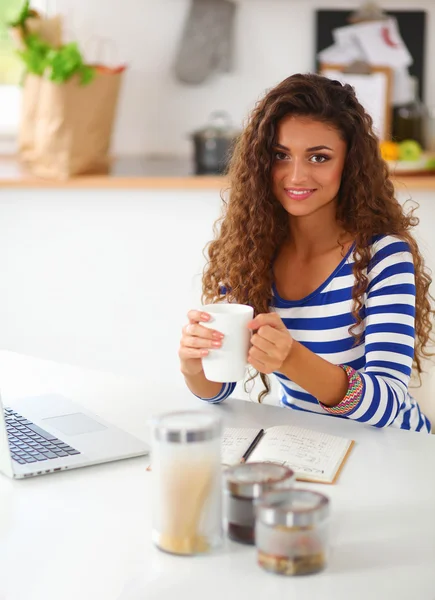 Retrato de mujer joven con taza contra fondo interior de la cocina — Foto de Stock