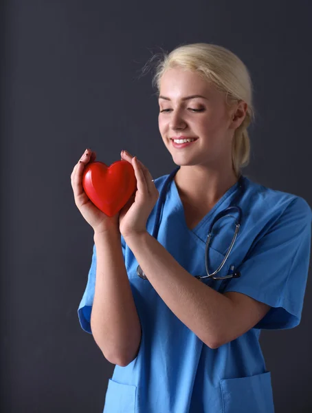 Doktor se stetoskopem drží srdce, izolované na šedém pozadí — Stock fotografie