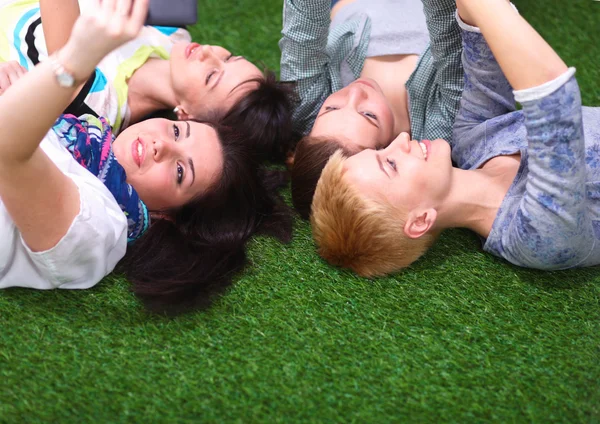 Quatro mulheres jovens deitadas na grama verde — Fotografia de Stock