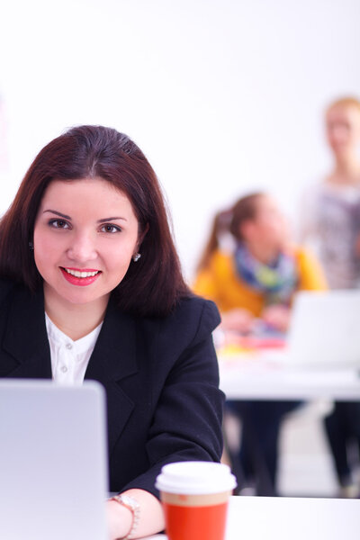 Attractive businesswoman sitting  on desk in the office with cup of coffee