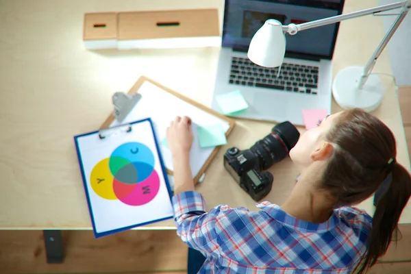 Vrouwelijke fotograaf zittend op het bureau met laptop — Stockfoto