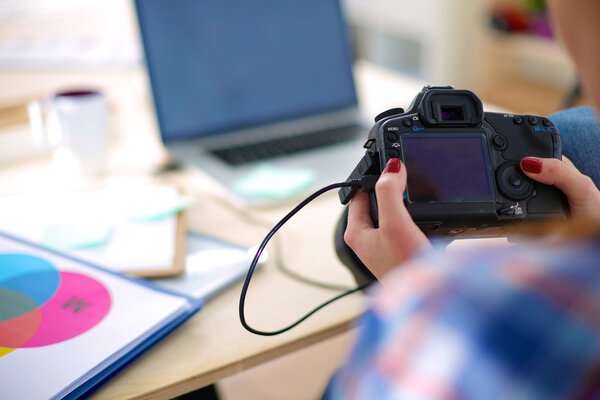 Женщина-фотограф сидит на столе с ноутбуком