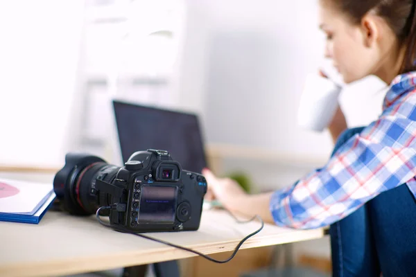 Kvinnlig fotograf sitter på skrivbordet med bärbar dator — Stockfoto