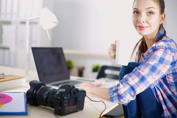 Kvinnlig fotograf sitter på skrivbordet med bärbar dator — Stockfoto