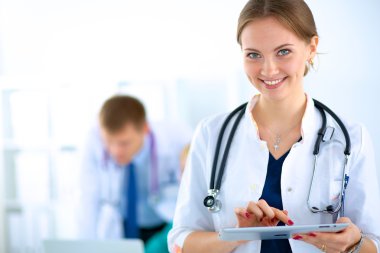 Genç bir doktor elinde bir tablet tutuyor.