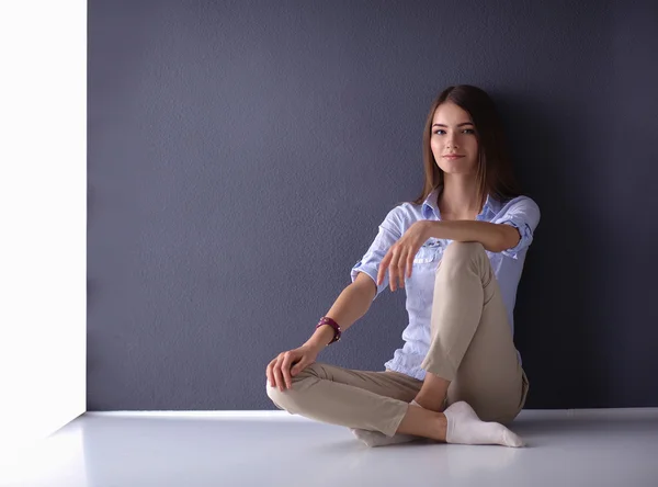 Jovem mulher sentada no chão perto da parede escura — Fotografia de Stock