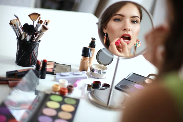 Mladá krásná žena, takže make-up zrcadla, sedící u stolu — Stock fotografie