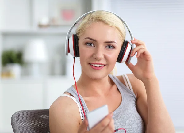 Joven hermosa mujer en casa sentada en el sofá y escuchando música — Foto de Stock