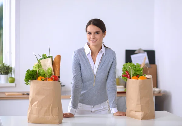 Woman with shopping bags in the kitchen at home, standing near desk — Stock Photo, Image