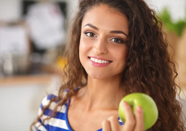 Счастливая молодая женщина ест яблоки на кухне — стоковое фото