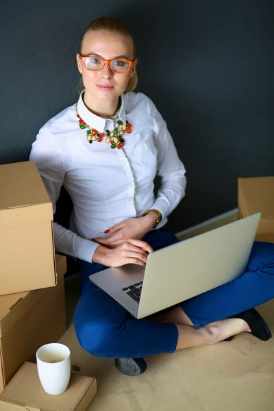 Femme assise sur le sol près d'une boîte avec ordinateur portable — Photo