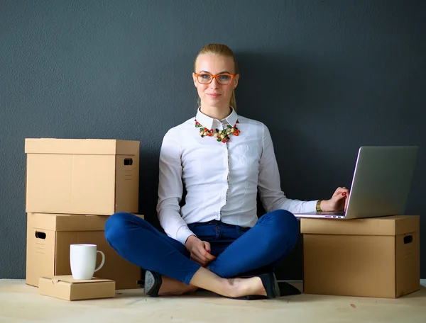 Mujer sentada en el suelo cerca de una caja con portátil —  Fotos de Stock