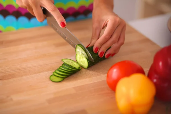 Junge Frau schneidet Gemüse in Küche — Stockfoto