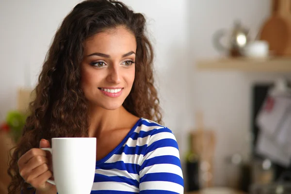 Retrato de mujer joven con taza contra fondo interior de la cocina — Foto de Stock