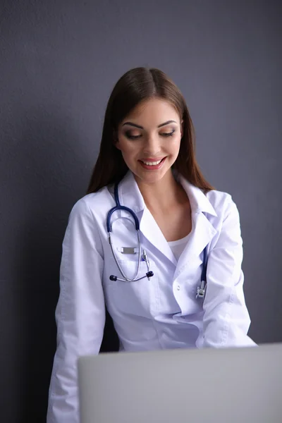 Femme médecin travaillant assis sur fond gris — Photo