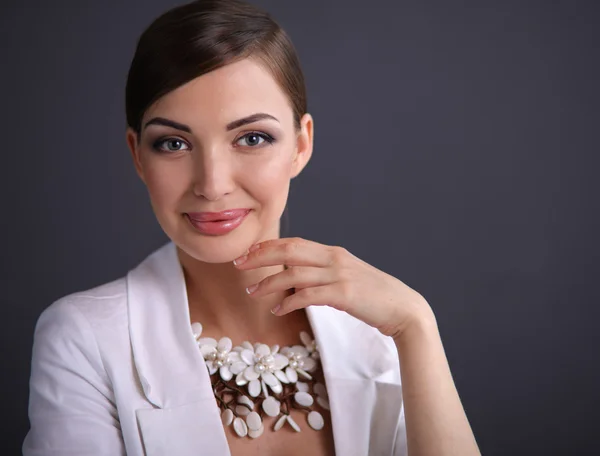 Portret van een jonge vrouw met parels, staande op een grijze achtergrond — Stockfoto