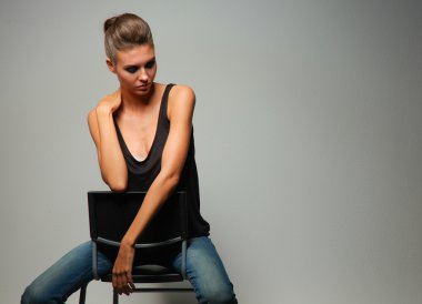 Gri arka plan üzerinde izole bir sandalye oturan güzel kadın