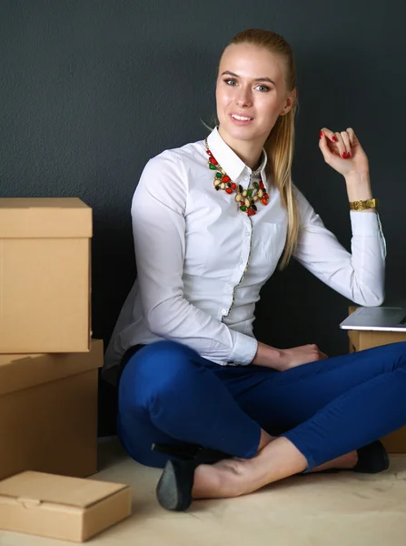 Mujer sentada en el suelo cerca de una caja con portátil —  Fotos de Stock