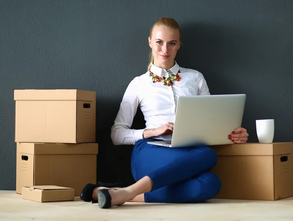 Woman sitting on the floor near a boxes  with laptop — Stock Photo, Image