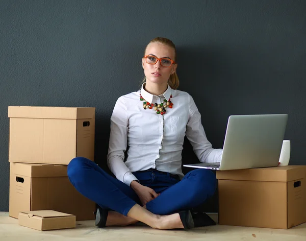 Donna seduta sul pavimento vicino a una scatola con computer portatile — Foto Stock