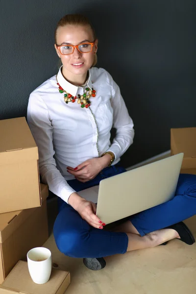 Vrouw zitten op de vloer in de buurt van een dozen met laptop — Stockfoto