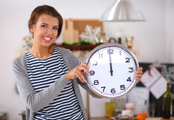 Szczęśliwa młoda kobieta pokazując zegar w Boże Narodzenie urządzone kuchnia — Zdjęcie stockowe