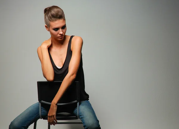 Beautiful woman sitting a chair, isolated on gray background — Stock Photo, Image