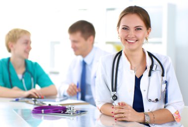 Masada oturan gülümseyen güzel genç bayan doktor.