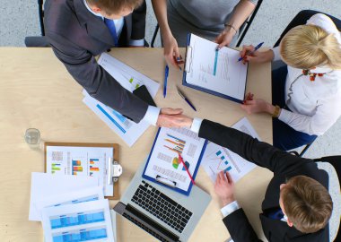 İş adamları el sıkışır, masada otururlar.