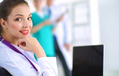 Masada oturan gülümseyen güzel genç bayan doktor.